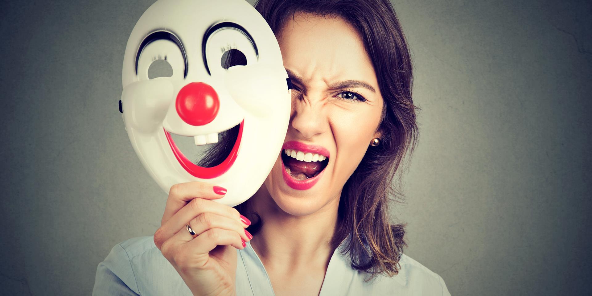 אישה "עושה פרצוף" בזמן שהיא מחזיקה מסכה של ליצן